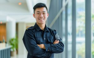 A young, confident security professional in uniform standing in a modern office building