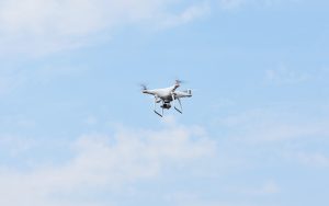 White quadcopter drone hovering steadily in a clear blue sky