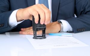 Hands of an official stamping a security certification document
