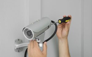 Professionally installing a wall-mounted security camera with a screwdriver